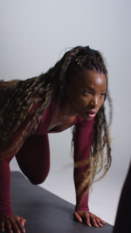 Vertical-Video-Studio-Shot-Of-Two-Women-Wearing-Gym-Fitness-Clothing-Facing-Each-Other-Exercising